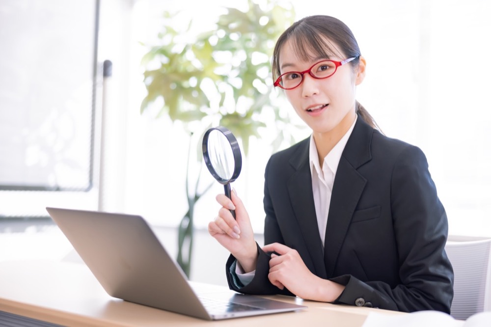 申請内容を虫眼鏡でチェックする専門スタッフ